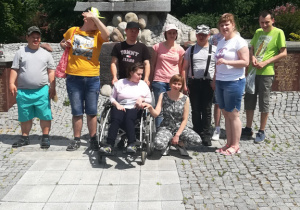 Zdjęcie grupy uczestników Programu Rehabilitacja 25 plus pod pomnikiem.